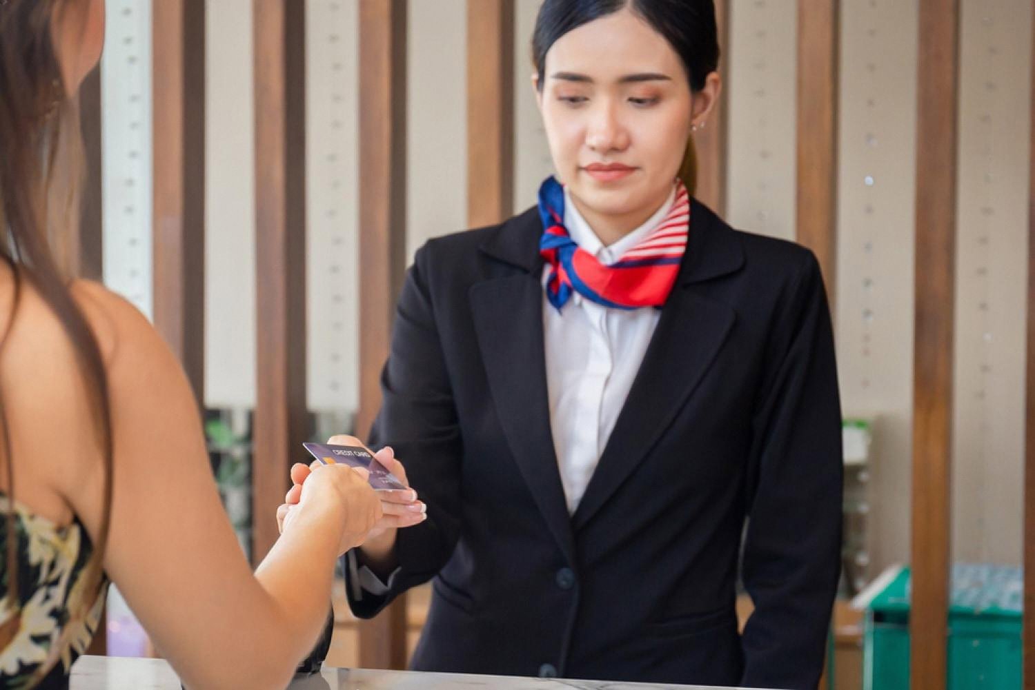 Guest handing a credit card to a hotel receptionist for a reservation payment